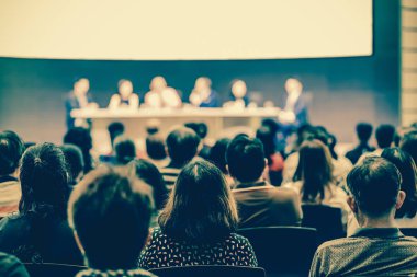 Seyirci arkadan görünüş hoparlörlere sahip konferans salonu veya seminer toplantıyla beyin fırtınası ve sahne, iş ve eğitim yatırım kavramı hakkında konuşmak vardır