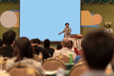 Konferans salonu veya Seminer Toplantı, iş ve eğitim kavramı sunusu ekran üzerinden sahnede rahat takım elbise ile Asya hoparlör closeup portresi