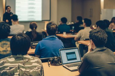 Arka tarafında oturan ve toplantı odası, olay ve seminer kavramı düşük ışıkta sahnede speackers dinleme kitlelere