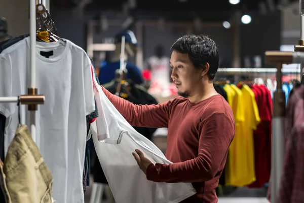 聪明的亚洲男人与胡子选择衣服在商店在购物中心 看白色 时尚和消费主义概念 — 图库照片