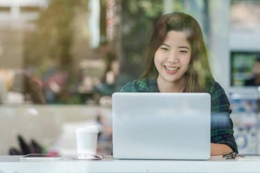 Modern ofis, işyeri sahibi ve girişimci konseptindeki cam yanında mutluluk eylemleri için teknoloji bilgisayarı kullanan Asyalı iş kadını portresi