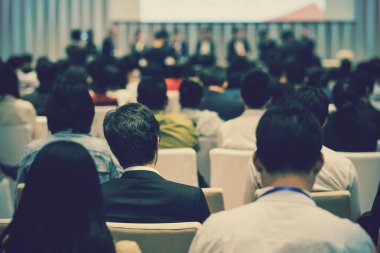 Sahnede, iş ve eğitim yatırım kavramı hakkında hoparlörlere sahip konferans salonu veya seminer toplantı seyirci görünümünde arka