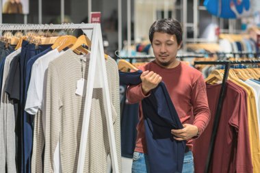 Giyim Mağazası, Alışveriş Merkezi, giysiler seçmek sakallı akıllı Asya adam renkli t-sshirts, moda ve tüketim kavramı arıyorsunuz.