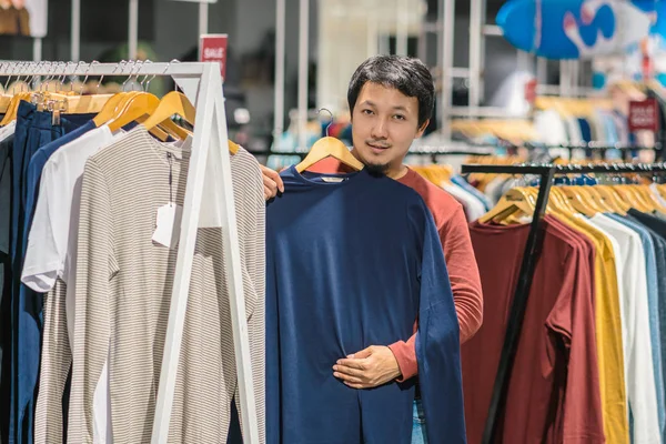 聪明的亚洲男人与胡子选择衣服在商店在购物中心 看着五颜六色的 时尚和消费主义的概念 — 图库照片