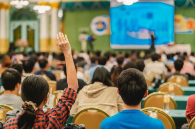 Konferans salonu veya Seminer Toplantı, iş ve eğitim kavramı sahne alanı'ndaki hoparlörden soruyu cevaplamak için el gösterilen seyirci arkadan görünüş