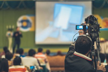 Arka yan Video fotoğraf için Asya hoparlör casual elbise ile sahne alanı'nda alarak kameraman mevcut konferans salonu veya Seminer Toplantı, olay ve seminer üretim kavramı içinde belgili tanımlık perde