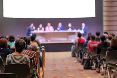 Seyirci arkadan görünüş hoparlörlere sahip konferans salonu veya seminer toplantıyla beyin fırtınası ve sahne, iş ve eğitim yatırım kavramı hakkında konuşmak vardır