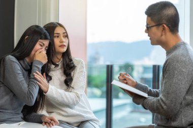 Asya erkek profesyonel psikolog doktor ev veya hastane muayene odası, Ruh sağlığı Kavramı modern oturma odasında ilişki sorunu var Lezbiyen severler hastalara danışın veren