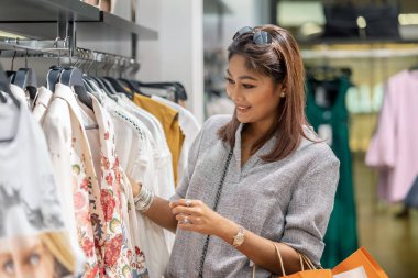 Mutlu Asyalı kadın mağaza dükkan bölümü merkezi mutlu eylemle giysiler ile cam yansıması seçmek