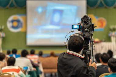 Arka yan Video fotoğraf için Asya hoparlör casual elbise ile sahne alanı'nda alarak kameraman mevcut konferans salonu veya Seminer Toplantı, olay ve seminer üretim kavramı içinde belgili tanımlık perde