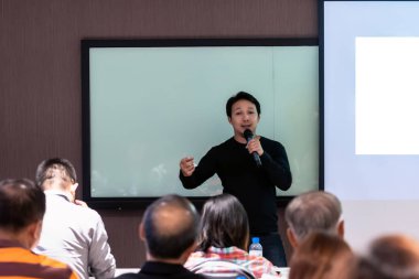 Asya hoparlör veya oda konferans salonu veya Seminer Toplantı odası, iş ve eğitim kavramı içinde belgili tanımlık perde ile sunulması önünde sahnede rahat takım elbise ile ders