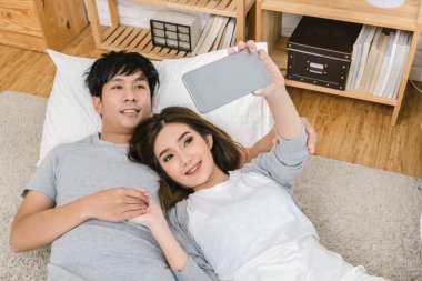 Mutlu Asya halı yatak, Çift selfie kavramı ile katta selfie için teknoloji akıllı telefon kullanarak aşık üstten görünüm,