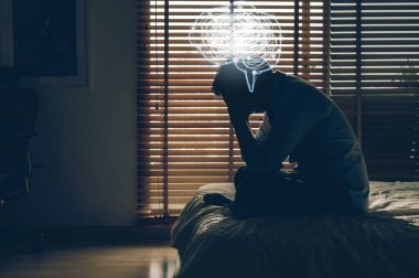 düşük ışık lı karanlık yatak odasında yatakta elleri başında oturan depresif adam ve düğüm doodle ile Polygonal beyin şekli, Depress ve stresli kavramı