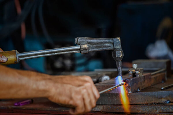 Closeup machinist hand bending the steel by torch in metalworking factory, lathe grinding metalworking industry concept