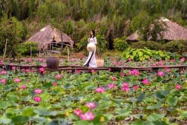 Büyük lotus gölü, Vietnam, aisan veya güneydoğu Asya seyahat konsepti ahşap köprü üzerinde yürüyen pembe lotus tutan geleneksel Vietnam şapkalı güzel Vietnamlı kadın portresi