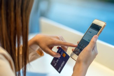 Online mağazada elbise dükkanı mağaza arka plan, teknoloji para cüzdanı ve online ödeme kavramı, kredi kartı mockup alışveriş için cep telefonu ile kredi kartı ile portre Asyalı kadın