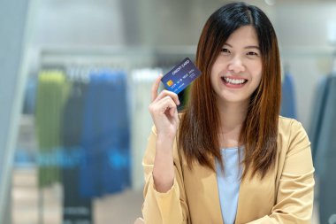Portre Asyalı kadın tutma ve giyim mağazası mağaza arka plan, teknoloji para cüzdan ve online ödeme konsepti üzerinde mağaza online alışveriş için kredi kartı sunan