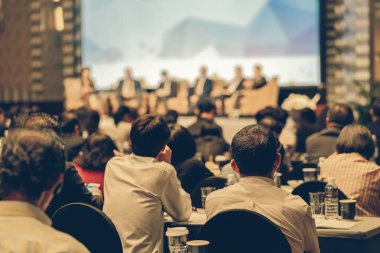 Konferans salonu veya Seminer Toplantı, iş ve eğitim yatırım kavramı hakkında sahnede hoparlörler dinleme seyirci arkadan görünüş