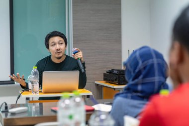 Asya Hoparlör veya konferans salonu veya seminer toplantı odası, iş ve eğitim kavramı ekran ile sunan oda önünde konuşma veren rahat takım elbise ile ders