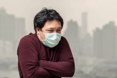 Yüksek kirlilik ve ağır sis bangkok cityscape arka sağlık kavramı üzerinde görebilirsiniz daire balkon, hava kirliliği ile soğuk karşı yüz maskesi giyen Asya adam