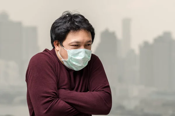 バンコクの街並み背景 ヘルスケアの概念上の汚染と重い霧を見ることができる高いアパートのバルコニーからの寒さで大気汚染に対してフェイス マスク身に着けているアジア人男性 — ストック写真