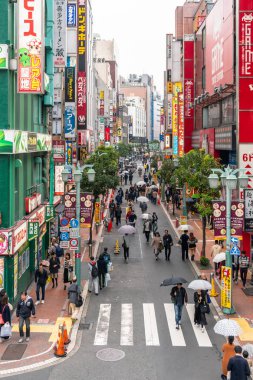 Tokyo, Japonya - Ekim 2017: Tanımsız Japon insanlar kalabalık yürüyüş ile 28 Ekim 2017 Jr Shinjuku istasyonu Tokyo, Japonya'da binalar arasında yağmur sokak.