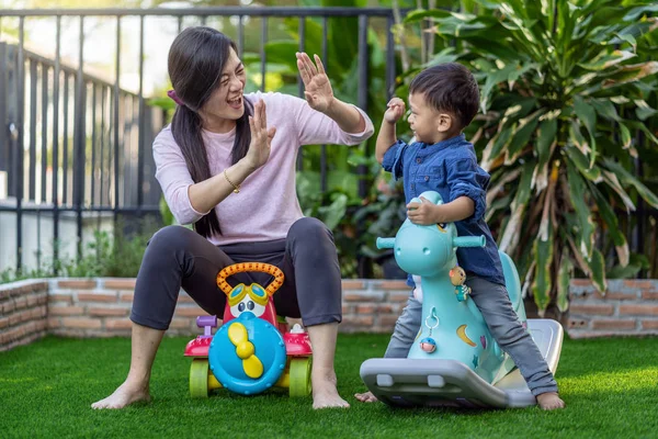 Asian single mom with son are playing with toy together when living in Front lawn of modern house for Self learning or home school, Family and single mom concept, selective focus