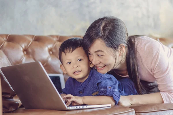 Asian Single mom with son are looking the cartoon via technology laptop and playing together when living in loft house for Self learning or home school,Family home school concept