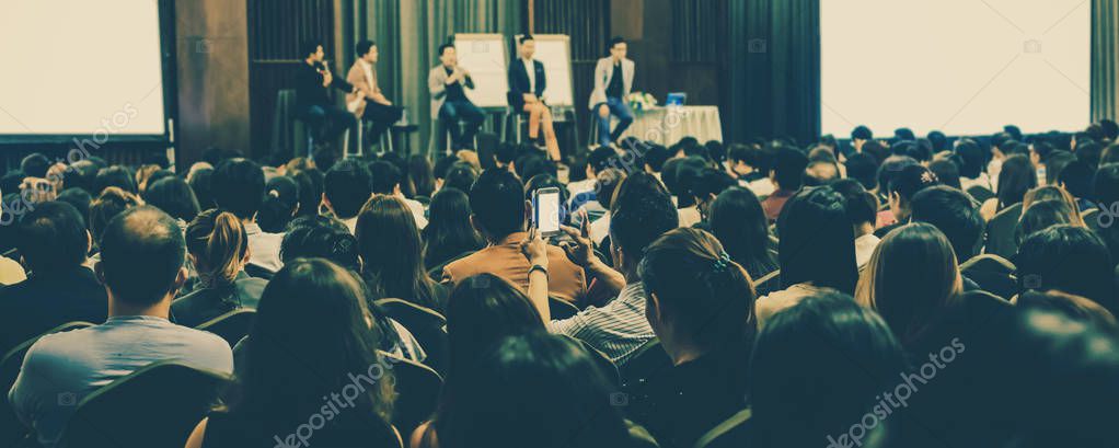 Banner of Speakers on the stage with Rear view of Audience in the conference hall or seminar meeting, business and education concept