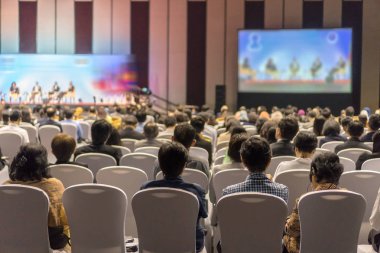 Konferans salonu veya Seminer Toplantı, iş ve eğitim yatırım kavramı hakkında sahnede hoparlörler dinleme seyirci arkadan görünüş