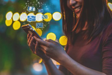 Açık parkta, İş ve Yaşam Tarzı konseptinde Like, Love, comment, people ve fovorite simgesi sayısı ile sosyal netwrok medya için akıllı telefon ve dokunmatik ekran kullanarak Asyalı kadının closeup el