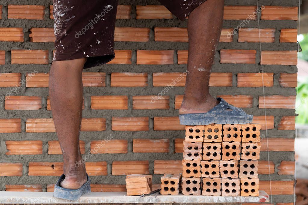 Closeup leg of professional construction worker laying bricks in new industrial site. construct industry and masonry concept