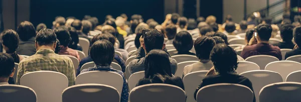 Banner cover page of Rear view of Audience listening Speakers on the stage in the conference hall or seminar meeting, business and education about investment concept