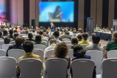 Konferans salonu veya Seminer Toplantı, iş ve eğitim yatırım kavramı hakkında sahnede hoparlörler dinleme seyirci arkadan görünüş