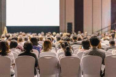 Konferans salonu veya Seminer Toplantı, iş ve eğitim yatırım kavramı hakkında sahnede hoparlörler dinleme seyirci arkadan görünüş