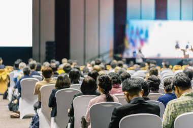 Konferans salonu veya Seminer Toplantı, iş ve eğitim yatırım kavramı hakkında sahnede hoparlörler dinleme seyirci arkadan görünüş
