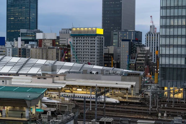 都心の街並みや建物の背景 交通コンセプトを中心に夕暮れ時のテラスから東京駅の列車トラスポートシーン — ストック写真