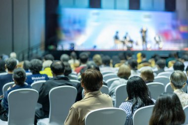 Konferans salonu veya Seminer Toplantı, iş ve eğitim yatırım kavramı hakkında sahnede hoparlörler dinleme seyirci arkadan görünüş