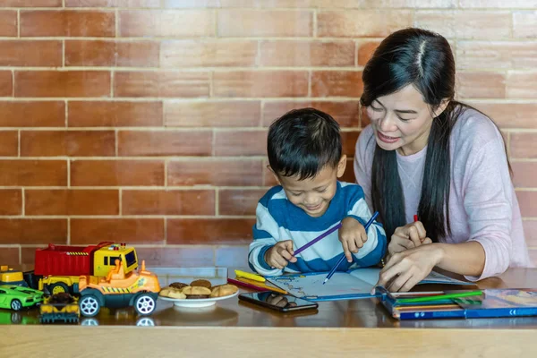 Asian single mom with son are drawing together when living in loft house for Self learning or home school, Family and single mom concept, selective focus