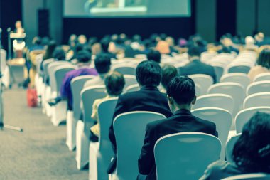 Konferans salonu veya Seminer Toplantı, iş ve eğitim yatırım kavramı hakkında sahnede hoparlörler dinleme seyirci arkadan görünüş