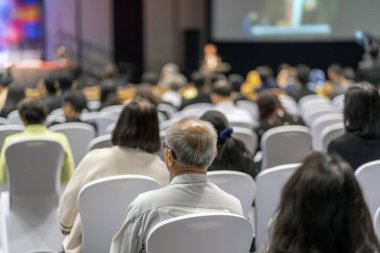 Konferans salonu veya Seminer Toplantı, iş ve eğitim yatırım kavramı hakkında sahnede hoparlörler dinleme seyirci arkadan görünüş