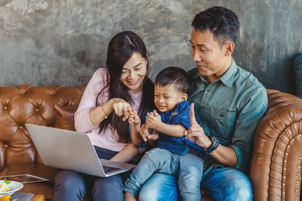 Asian family with son are looking the cartoon via technology laptop and playing together when living in loft house for Self learning or home school,Family home school concept