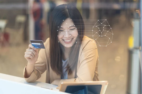 Asian women using the technology tablet for access control by face recognition in private identification step when online shopping with the credit card, credit card mockup, online payment concept,