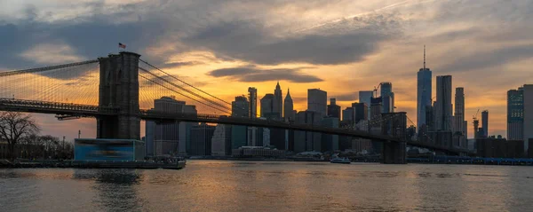 夕暮れ時に東の川に架かるブルックリン橋 宇佐ダウンタウンのスカイライン 建築と交通コンセプトを持つニューヨーク市街地のバナーとカバーシーン — ストック写真