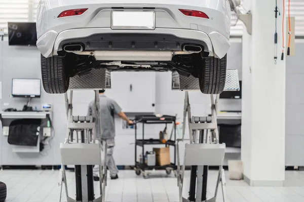 Back side of Car lifted in automobile service and Asian mechanic Checking and torch tire in maintainance service center which is a part of showroom, technician or professional work for customer concept