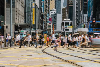 HONG KONG, HONG KONG - JULY 2019 : Crowd of Traffic car and tram with Unrecognizable pedestrians crossing over the yellow color crosswalk around Central District on July 5, 2019, Hong Kong clipart