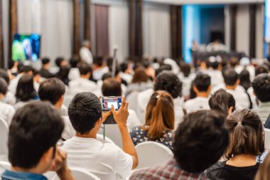 Dinleyici dinleme Konuşmacıları'nın arka görünümü ve konferans salonunda veya seminer toplantı ve atölye etkinliğinde fotoğraf çekmek için cep telefonu kullanmak, yatırım konsepti ile ilgili iş ve eğitim