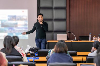 Asya Hoparlör veya konferans salonu veya seminer toplantı odasında projektör ekranı üzerinden sunum sahnede rahat takım elbise ile ders Seyirci, iş eğitimi ve Seminer kavramı