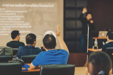 Konferans salonu veya Seminer Toplantı, iş ve eğitim kavramı sahne alanı'ndaki hoparlörden soruyu cevaplamak için el gösterilen seyirci arkadan görünüş