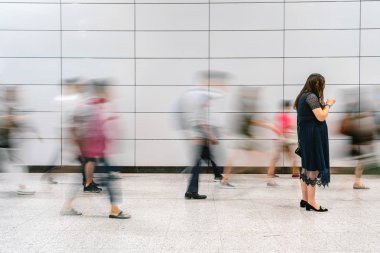 Beyaz arka plan, sokak fotoğrafçılığı, iş banliyö kavramı ile ulaşım kavşak merkezinde hareketli bulanık hareket gezgin arasında ayakta ve cep telefonu kullanarak tanınmayan çalışan kadın